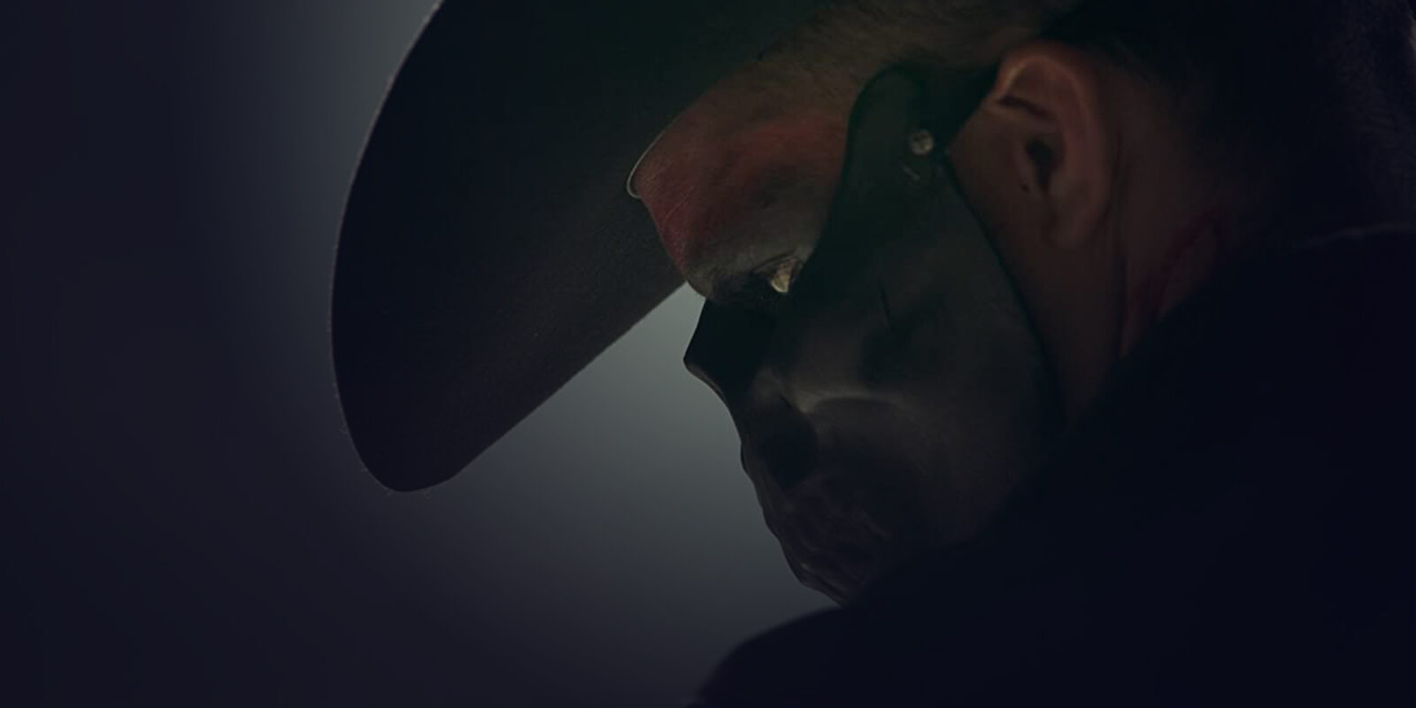 Close-up of a man's profile wearing a black skull mask up to his nose