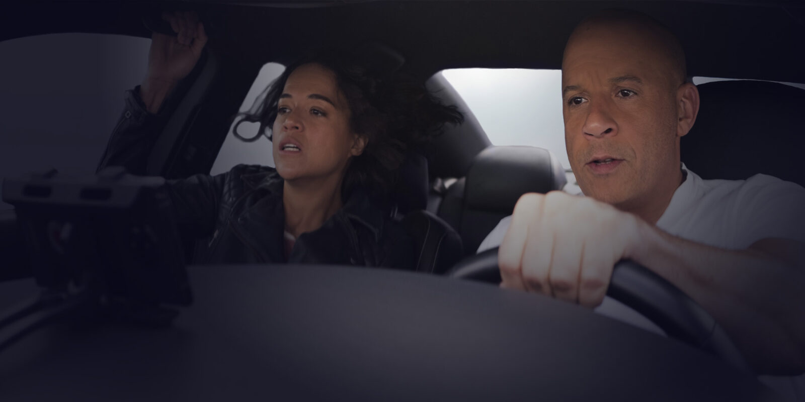 Close-up of a man holding the wheel of a car with a woman sitting next to him