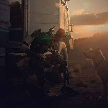 Long shot of a robot sitting on the step of an RV and leaning towards a small dog