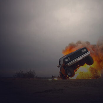 Flaming pick up truck moving in the middle of the desert