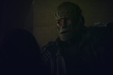 Close-up of a individual with red eyes wearing an iron mask
