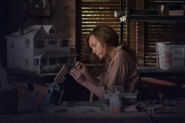 A women painting a doll house