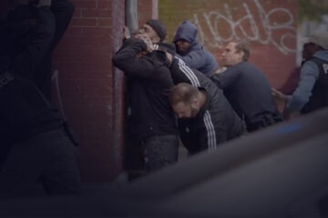 People leaning against the wall being searched by the police