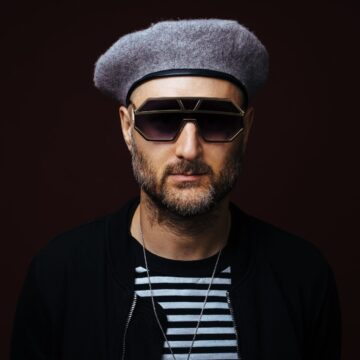 Close up of Sam I wearing big sunglasses and a beret