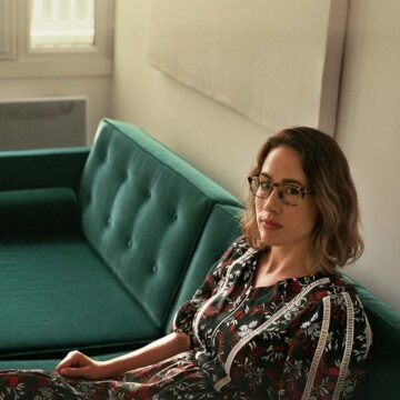 Artist Carly Paradis looking at the camera while sitting on a couch