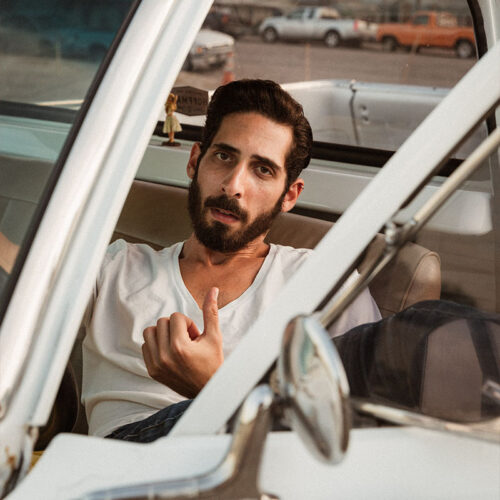 Composer Danny Schnair sitting in the driver's seat of a car