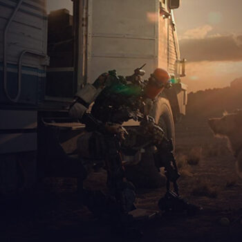 Long shot of a robot sitting on the step of an RV and leaning towards a small dog