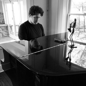 Composer Leland Cox sitting at a piano