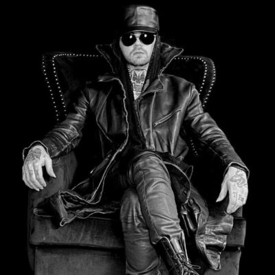Composer Gost sitting on an armchair wearing  a cap and sunglasses
